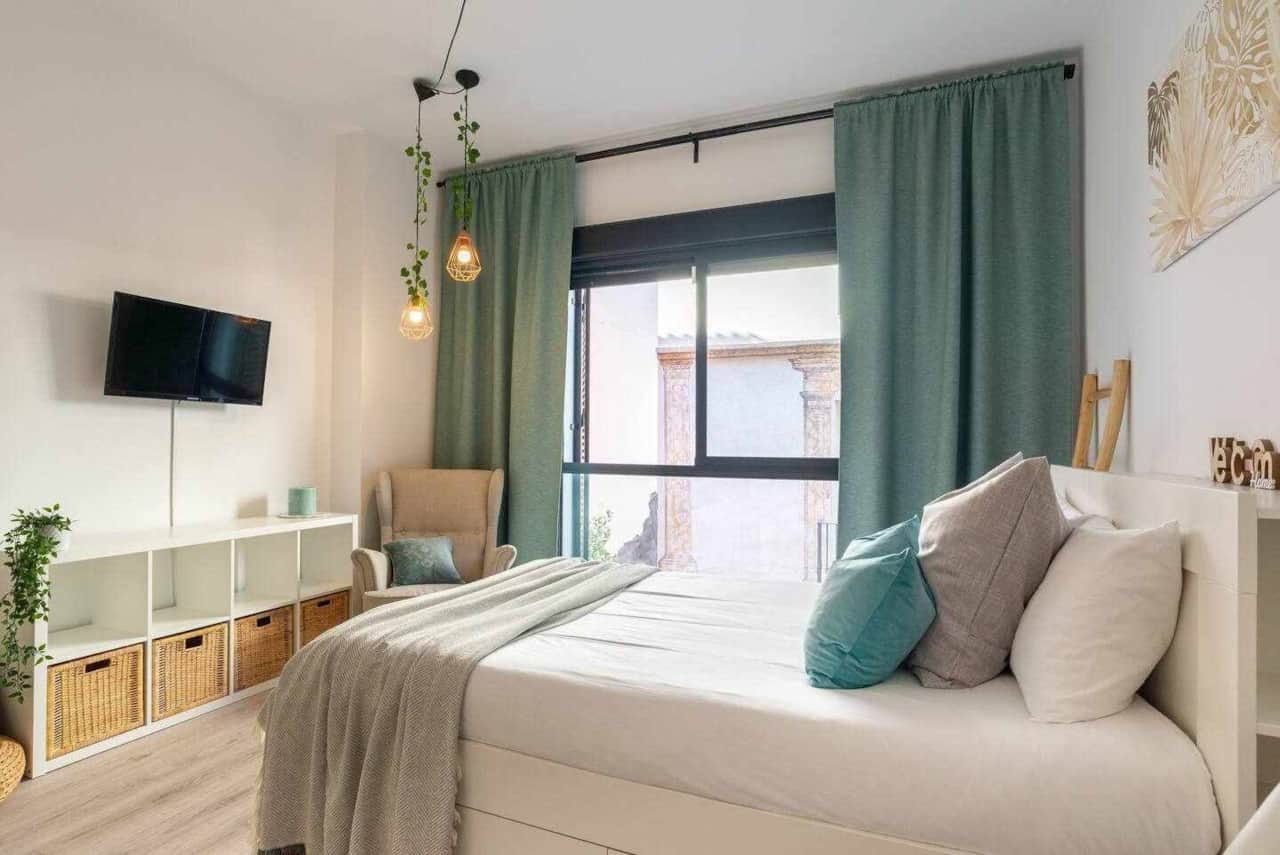 Soft double bed beside floor-to-ceiling windows and blackout curtains.