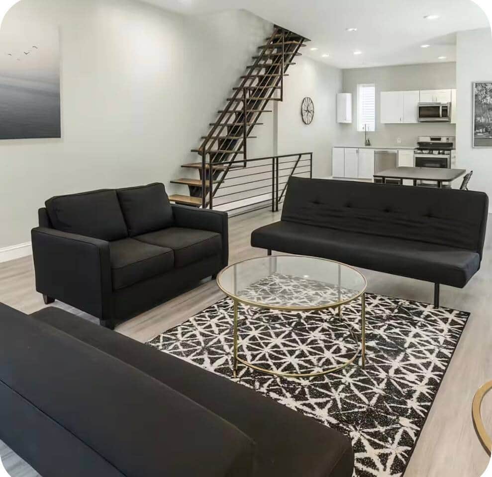 spacious living room featuring a large flat-screen TV and 3 comfortable futon sofa beds, providing plenty of seating during the day and extra sleeping space at night. The open-concept layout connects directly to the kitchen and dining area.