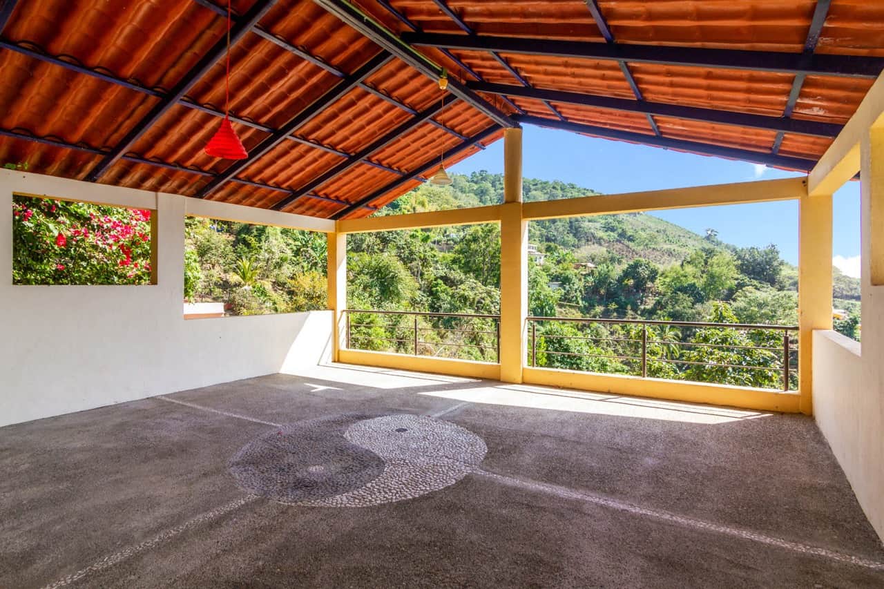 Terraza techada con mosaico de yin yang en piedra y vista a la selva