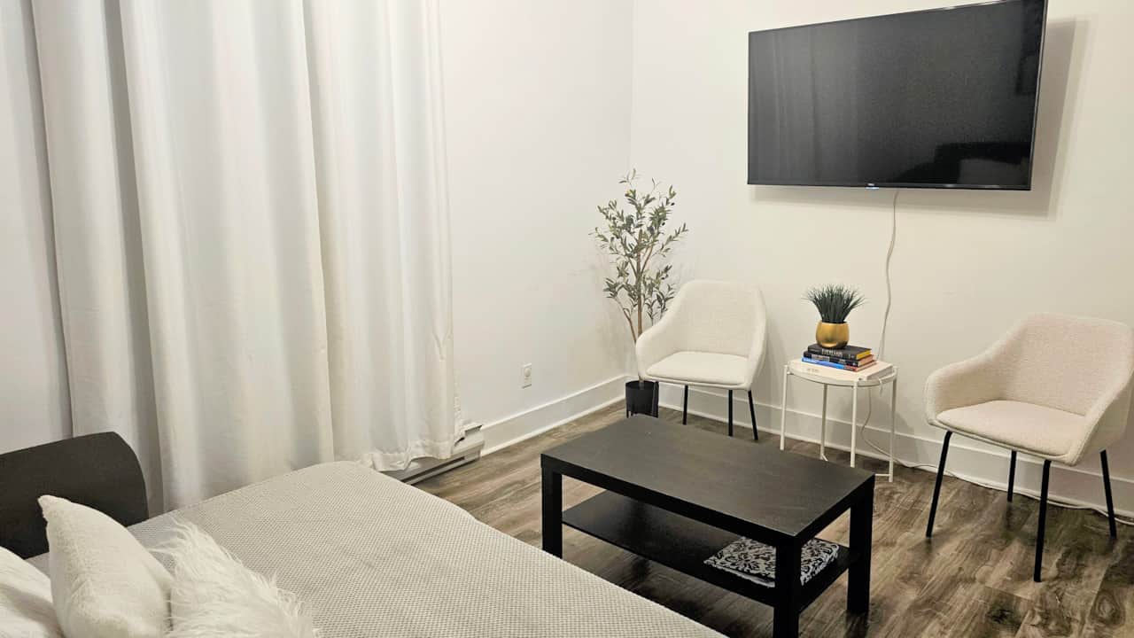 Cozy living room with seating area, wall-mounted TV, and minimalist decor in a main-floor apartment 