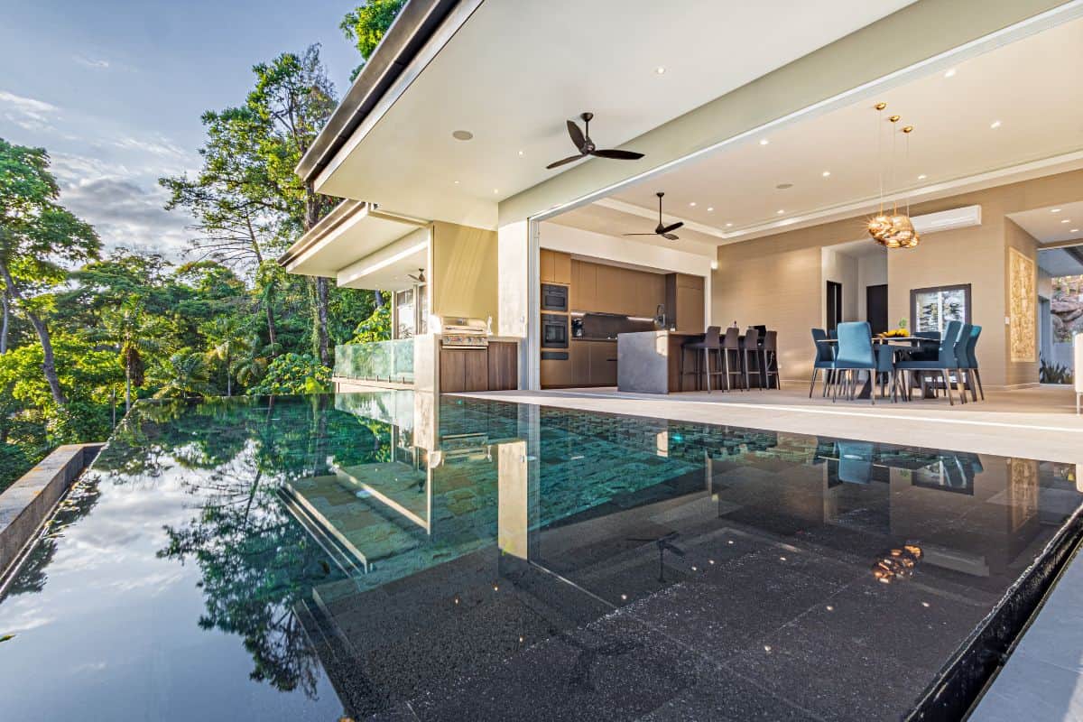 Infinity pool reflecting tropical rainforest at dusk; indoor-outdoor living at Villa Sueño