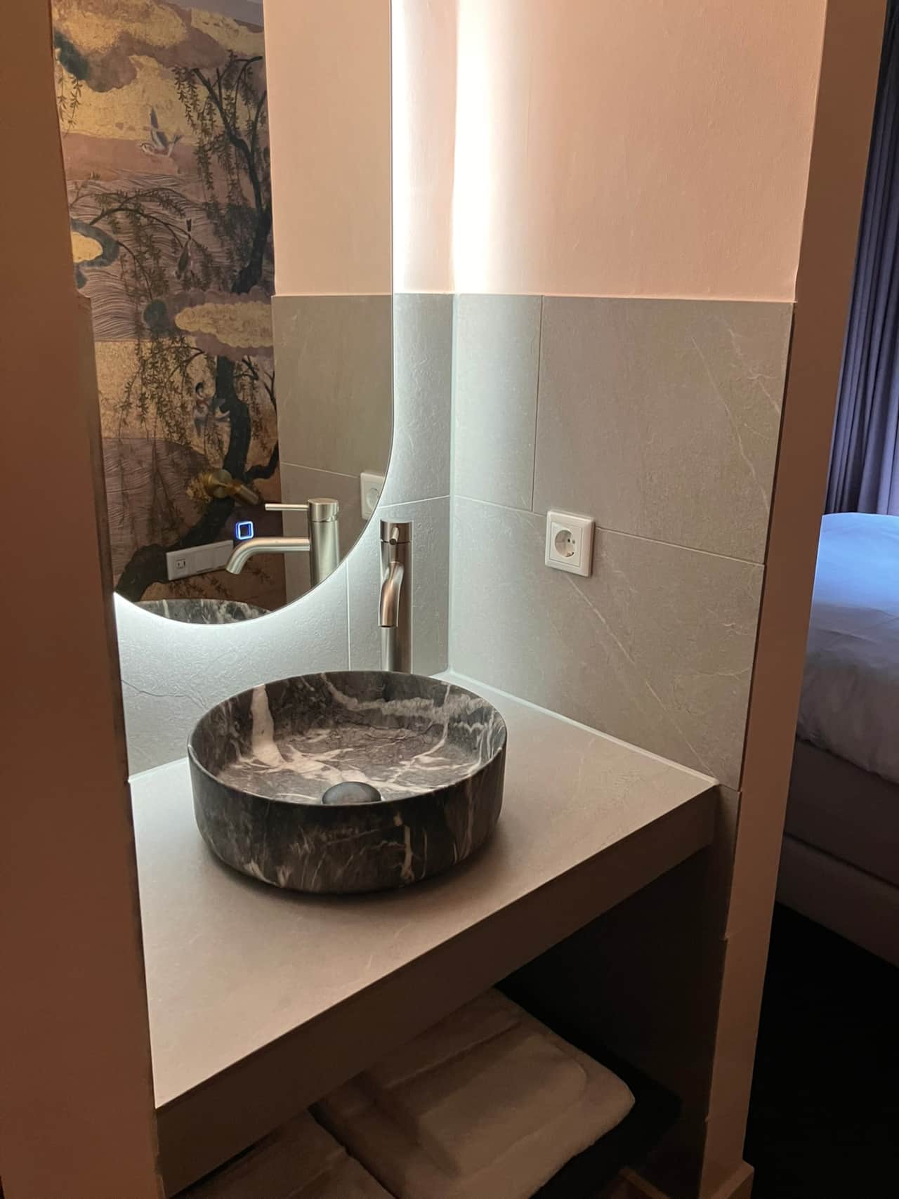 Robinah Suite bathroom vanity with a round stone vessel sink and backlit mirror