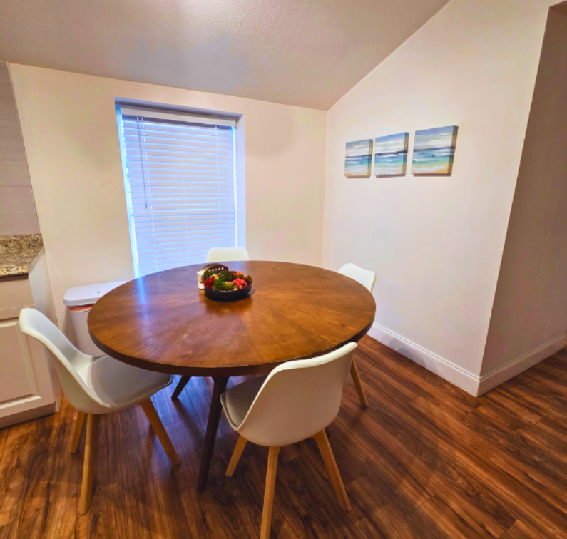 Dining area with a beautiful window, elegant blinds, wall art, and seating for four. Lakeland, FL