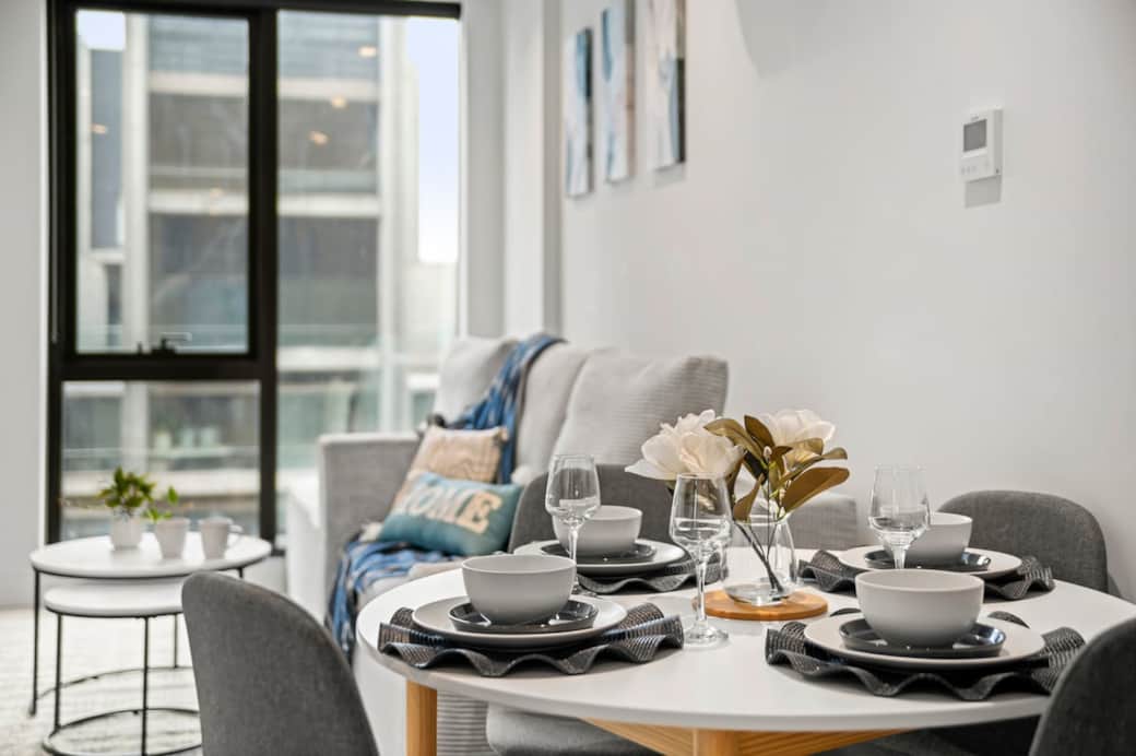 The dining area features a modern table set for four, perfect for enjoying meals, working, or catching up over coffee. Positioned within the open-plan living space, it offers a bright and comfortable setting for both dining and relaxation.