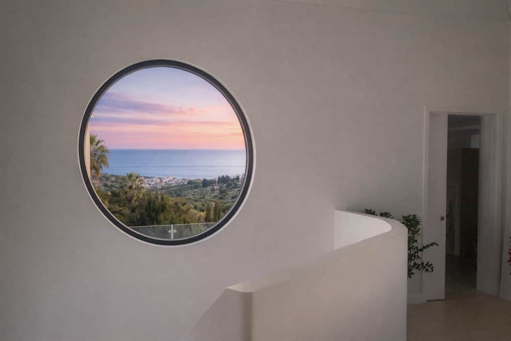 Round window framing the sea at sunset, upstairs at Villa Luz Bliss