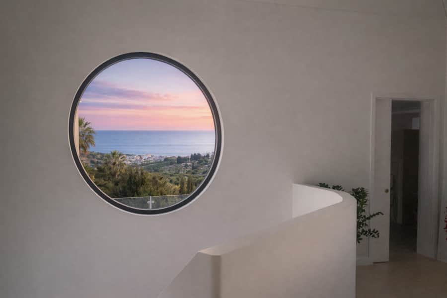 Round window framing the sea inside Villa Luz Bliss