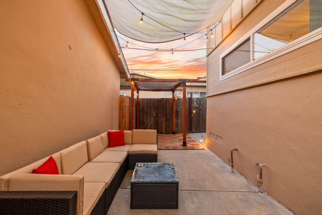 Private outdoor patio with cozy sectional seating, string lights, and shaded pergola