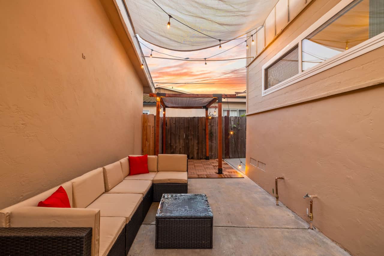 Private outdoor patio with cozy sectional seating, string lights, and shaded pergola