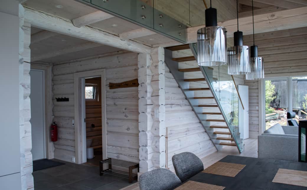 The staircase in light wood, a doorway open to the timber outside.