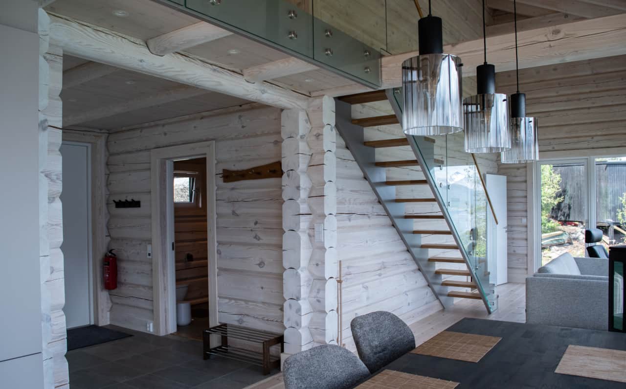 The staircase in light wood, a doorway open to the timber outside.