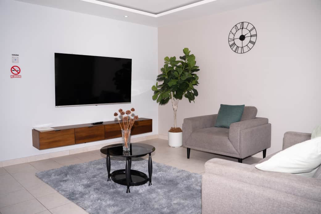 Sunlit lounge with mounted TV, A/C & curated decor — unwind after Kingston days