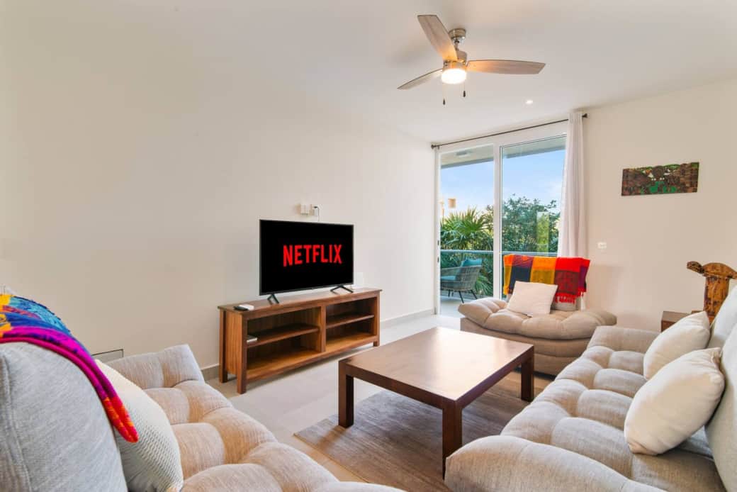 Cozy living space with plush couch, smart TV, AC, and balcony.