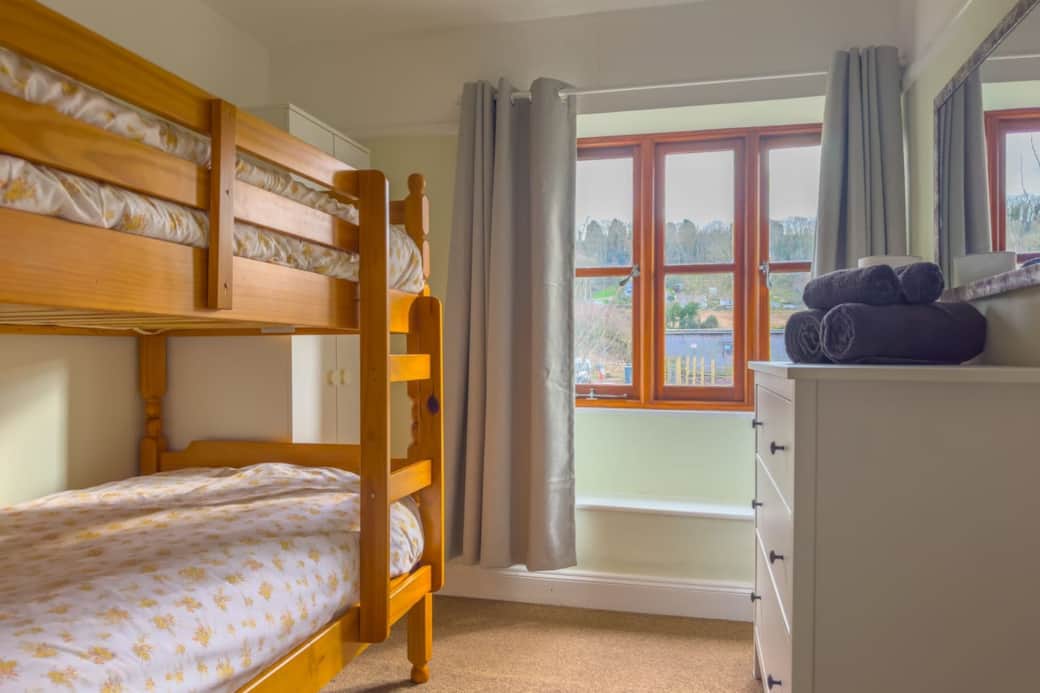 twin room with bunk beds, wardrobe, chest of drawers and garden view
