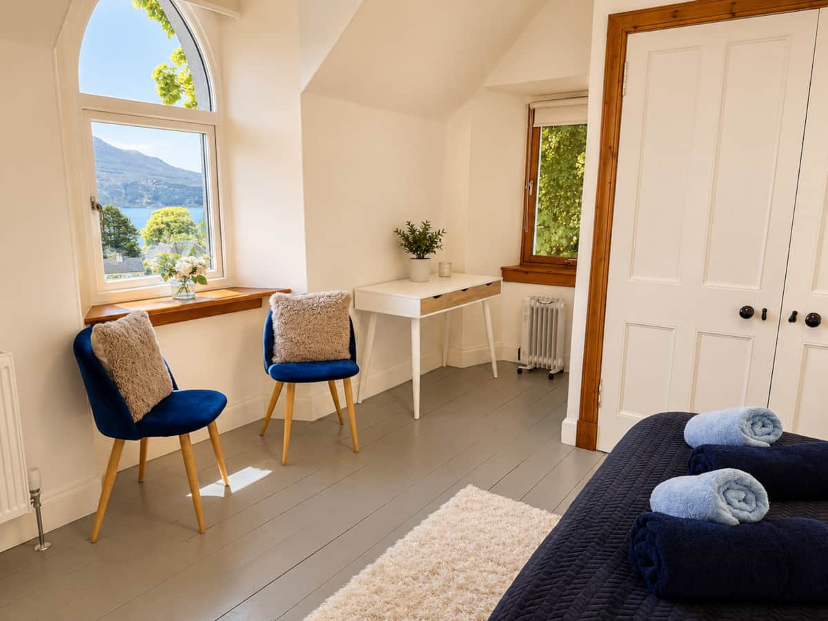 Velvet chairs and a desk by the arched window in Bedroom 1.