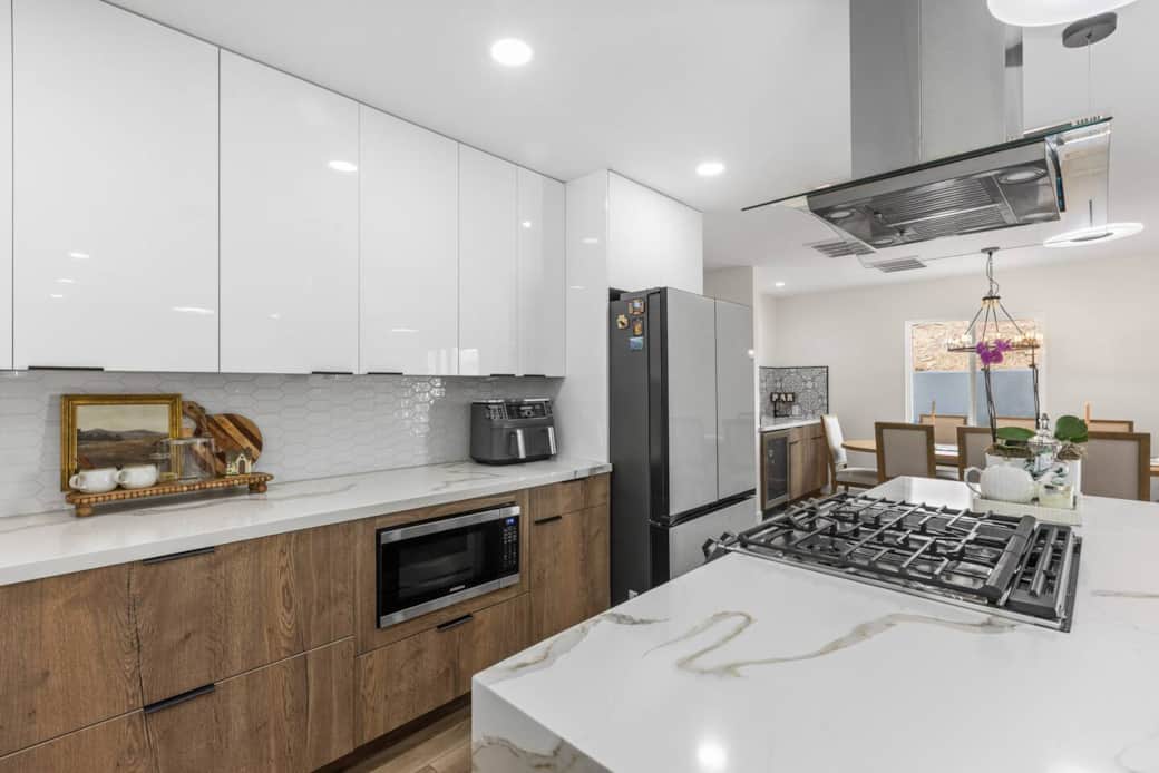 Modern kitchen with wood cabinets white finishes and a spacious layout with double door fridge.