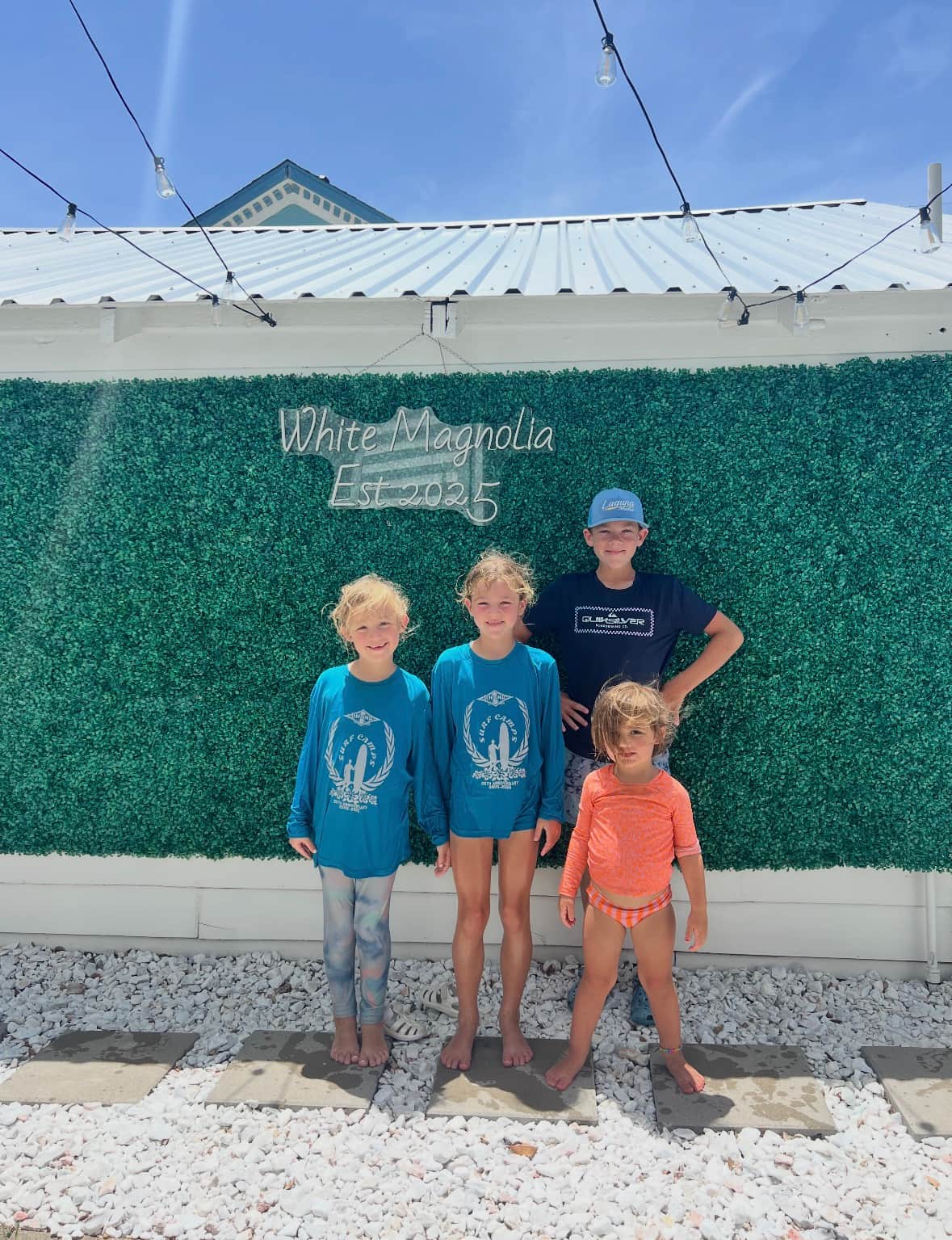 Guests posing at the White Magnolia Galveston courtyard photo wall