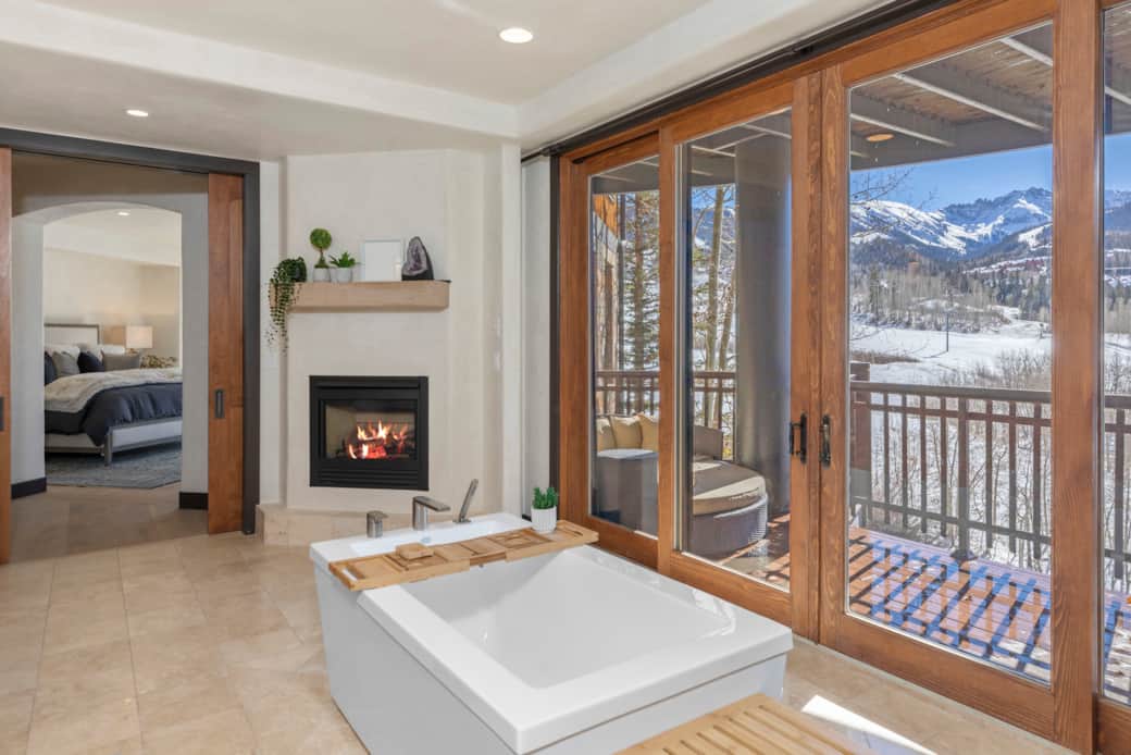 The primary suite ensuite bathroom offers a large shower, gas fireplace and tub overlooking skiing